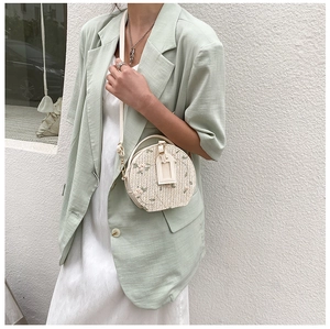 Straw circular crossbody bag with floral embroidery shown on model in street style shot