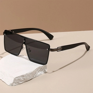 Fashionable oversized square black sunglasses with metal hinges on a stone pedestal