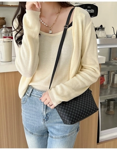Detailed view of a black crossbody bag with vintage geometric prints on a casual outfit