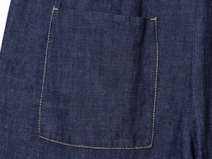 Dettaglio della tasca di una camicia di jeans blu scuro con cuciture arancioni a contrasto