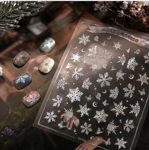 Macro detail of 3D embossed snowflake nail stickers with silver glitter and moon designs