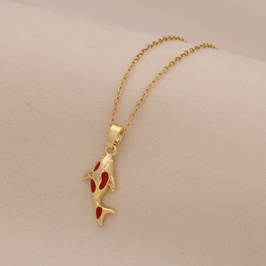 Close-up of golden koi fish pendant necklace with red enamel and sparkling gem eye