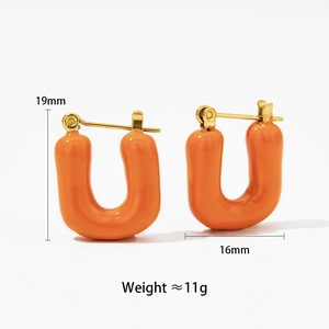 Détail macro de boucles d'oreilles U en émail orange avec touches dorées et dimensions