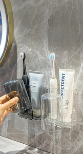 Detail of wall-mounted toothbrush holder with transparent cups on marble wall