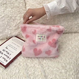 Detail of hand opening pink plush leopard heart cosmetic bag with soft texture