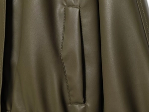 Detailed close-up showing the pocket stitching and faux leather texture of olive jacket