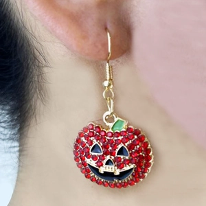 Close-up of Halloween pumpkin earrings with red rhinestones on a gold setting