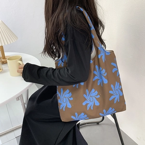 Detail of canvas tote bag with blue orchid patterns in a cozy cafe setting