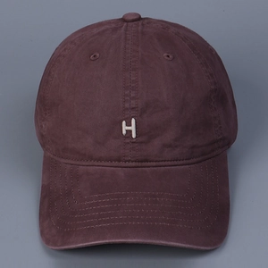 Close-up of white embroidered letter H on washed cotton baseball cap with vintage texture