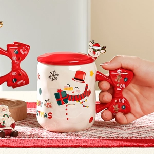 Detail of Christmas ceramic mug with snowman pattern, red lid and 3D bow handle