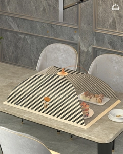 Detail of a foldable mesh food cover with sturdy ribs and striped pattern on the dining table
