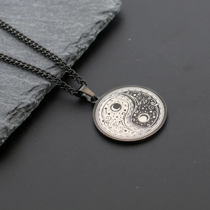 Macro shot of Yin Yang Tai Chi pendant with sun and moon motifs on a slate rock background