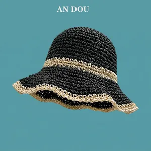 Detail of hand-woven straw hat showing two-tone black and beige knit with wavy brim