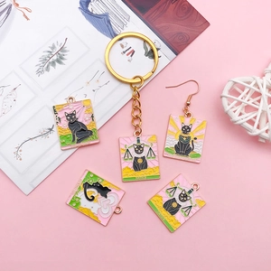 Flat lay of black cat tarot pendants featuring enamel Justice and Lovers designs