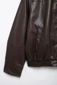 Detail of dark brown faux leather bomber jacket showing sleeve cuff and elastic hem