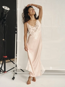 Détail d'une robe longue en satin rose avec dentelle blanche et fente latérale