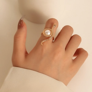 Detailed close-up of a golden snake ring wrapping around a central white pearl on a finger