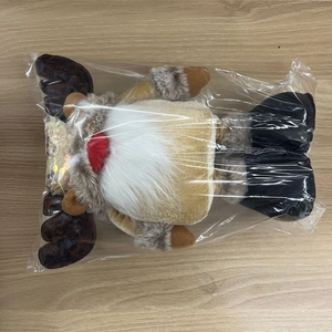 Flat lay of a Christmas reindeer gnome plush doll in clear packaging on a wooden table