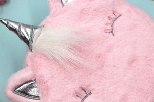 Vue détaillée du sac licorne en peluche rose avec corne argentée et broderies
