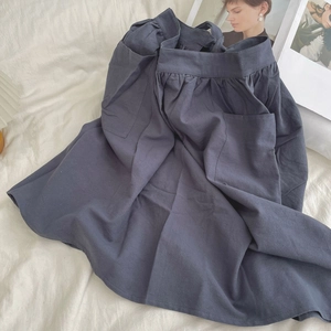 Detail view of dark grey cotton waist apron with pleated elastic waistband and side pocket