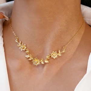 Gros plan d'un collier floral doré serti de zircons sur une chemise blanche