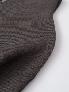 Detail of dark grey knit fabric texture with smooth silver metal zipper on a stand collar