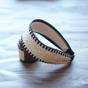 Detailed view of woven raffia headband with black decorative stitching and herringbone texture
