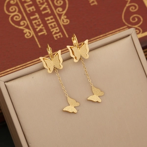 Golden matte butterfly pendant earrings on a jewelry box with an elegant aesthetic