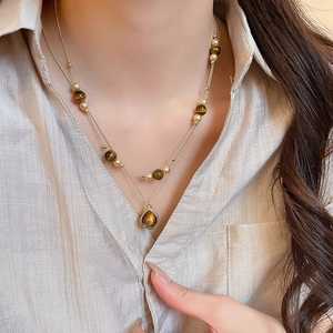 Macro view of double-layer necklace featuring tiger eye stone beads and gold metal chain