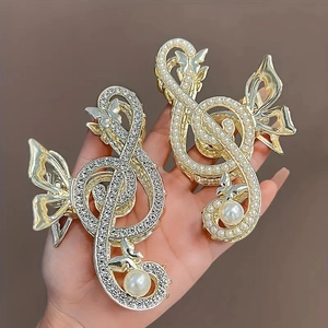Detail of treble clef hair claws with pearls and rhinestones in gold and silver finish