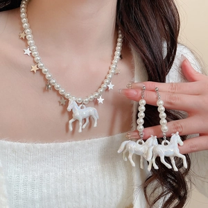 Détail d'un ensemble collier et boucles d'oreilles avec perles et pendentifs cheval