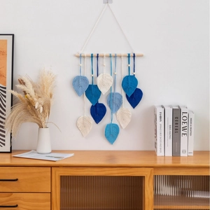 Detail of handcrafted macrame wall hanging featuring blue leaf-shaped woven cotton designs