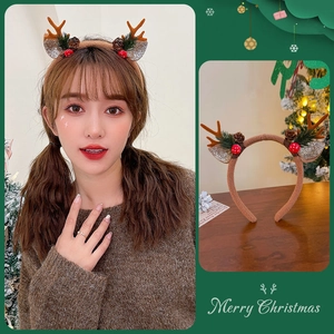 Detailed view of plush reindeer antler headband with pine cones and berries for Christmas