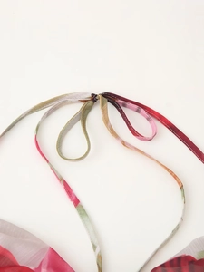 Détail de l'imprimé floral coloré et des bretelles licou sur une robe dos nu sexy