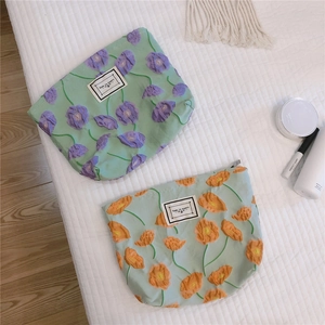 Detail of floral embroidery on pastel green and blue fabric makeup pouches with zippers