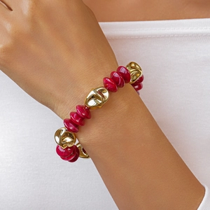 Detailed shot of vintage acrylic red beads and irregular golden metal beads on wrist