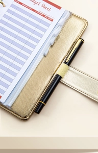Close-up of gold PU leather budget binder with pen loop and printed budget sheets