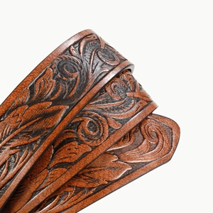 Detailed macro of brown leather belt featuring vintage embossed floral patterns and textures