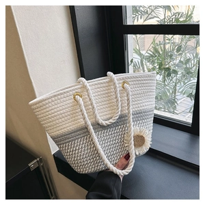 Detail of woven straw tote bag with daisy ornament and white rope handle