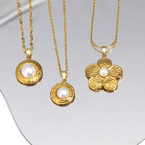 Detailed view of 18K gold-plated floral shell pendants with pearls on a mirror surface
