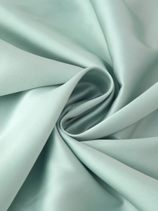 Dettaglio dell'elegante tessuto di raso verde menta con texture setosa e pieghe