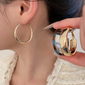 Detail of chunky gold metal hoop earrings and tortoise shell resin earrings on model