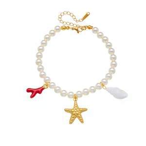 Bracelet en perles style océan avec breloques coquillage et étoile de mer dorées sur fond blanc