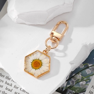Detailed macro shot of a white daisy flower pendant with hexagonal gold metal frame