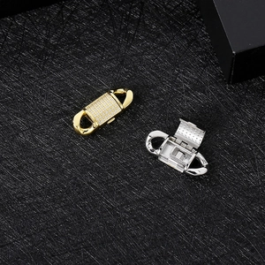 Detail of gold and silver iced out Cuban fold-over clasps on a black textured surface