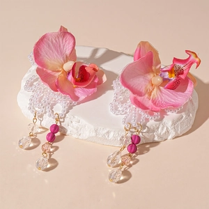 Close-up of pink fabric orchid earrings with pearl tassels and crystal drop accents