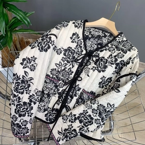Detail of diamond-quilted cotton jacket featuring floral print and black ribbon ties