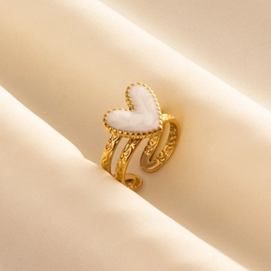 Golden heart-shaped open ring with white inlay and floral relief on beige satin