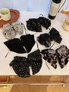 Detail of six French chiffon bow hair clips with floral and sequin patterns on a white table