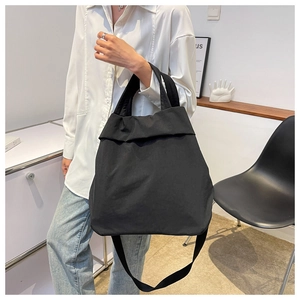 Close-up of lightweight black nylon tote bag worn by a model in a minimalist setting